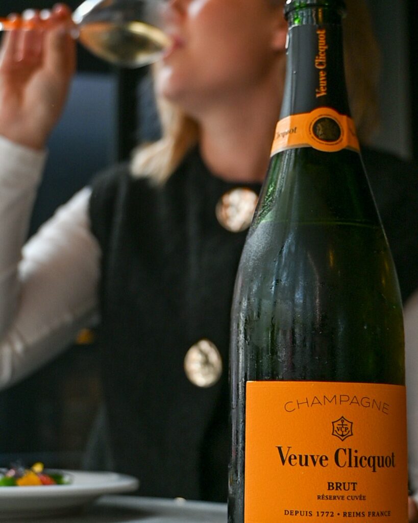 Bouteille de Champagne Veuve Clicquot et une cliente qui déguste une coupe